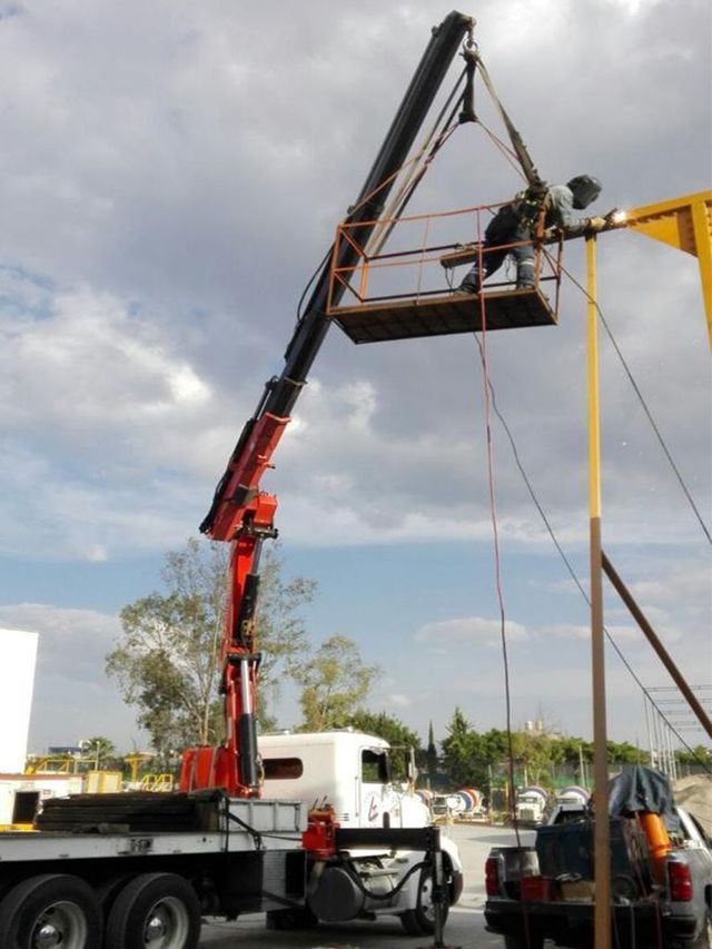 Un hombre está trabajando en un poste con una grúa adjunta