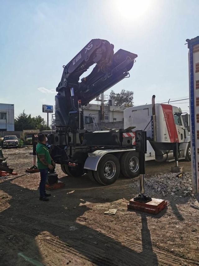 Un hombre está parado junto a un camión con una grúa adjunta.