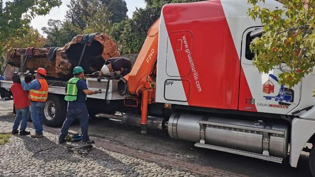 Un grupo de hombres está remolcando un camión rojo y blanco.