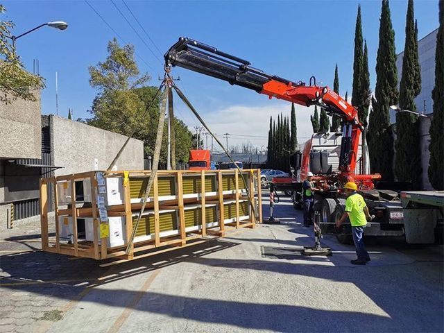 Una grúa levanta una caja de madera en un camión