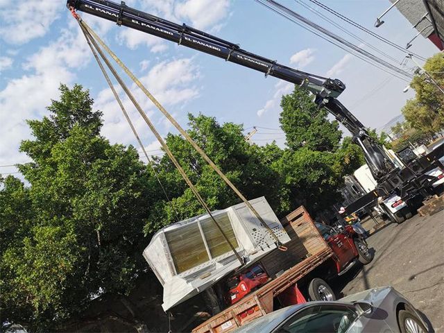 Una grúa levanta un barco sobre un camión.