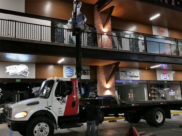 Una grúa está estacionada frente a un edificio con at & t escrito en él