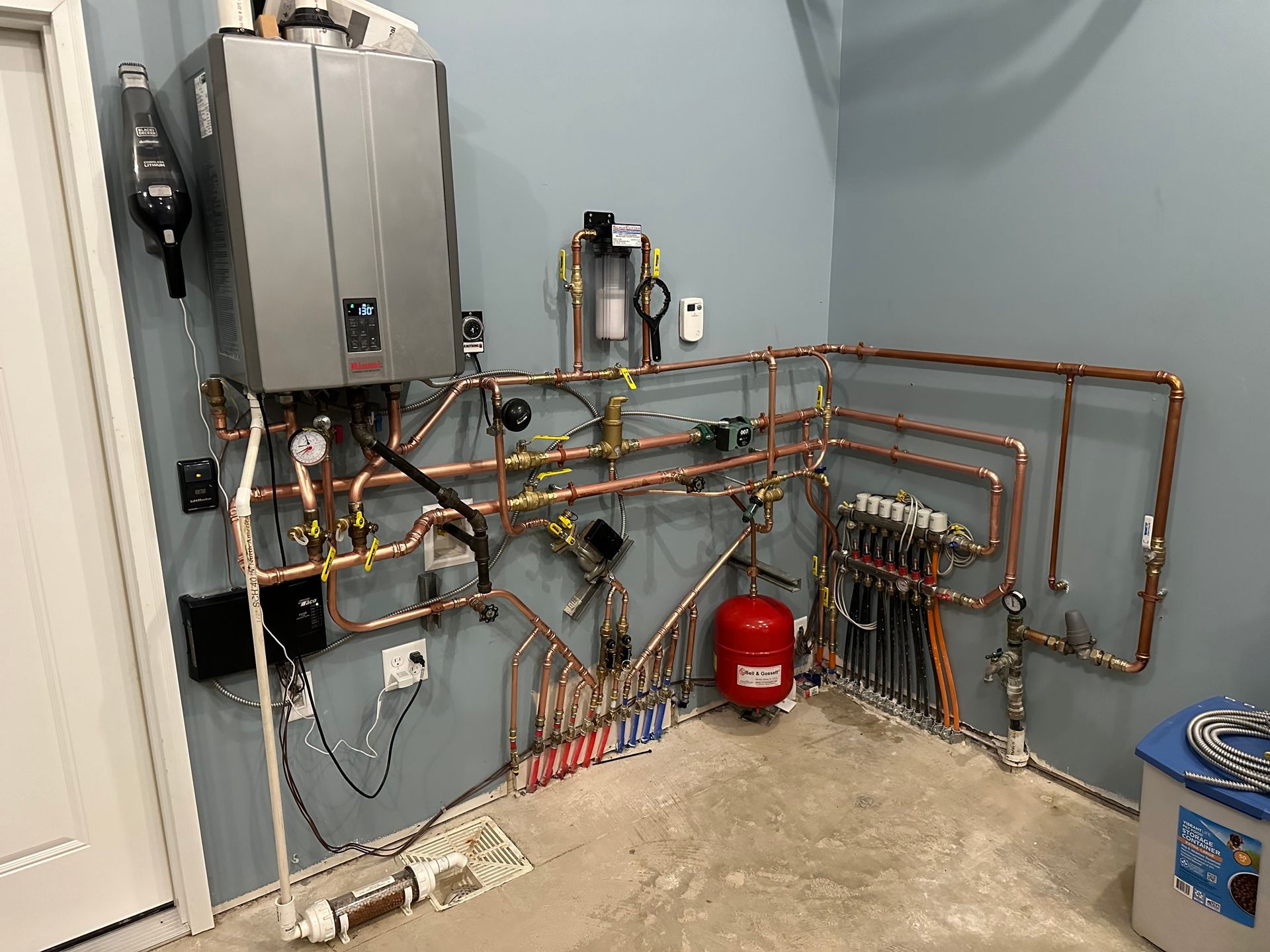 A room with a boiler and pipes on the wall.