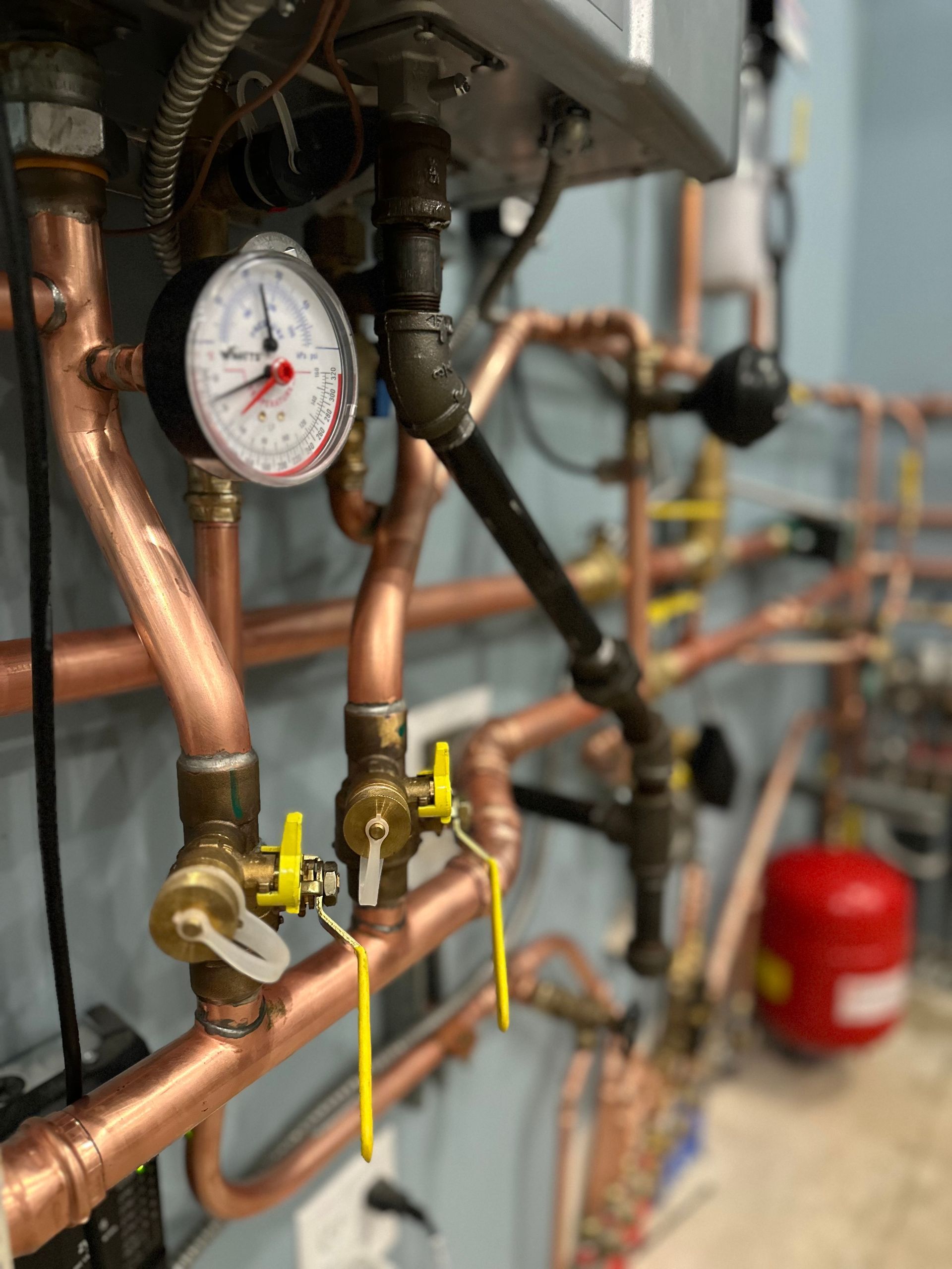 A close up of copper pipes with a gauge on top