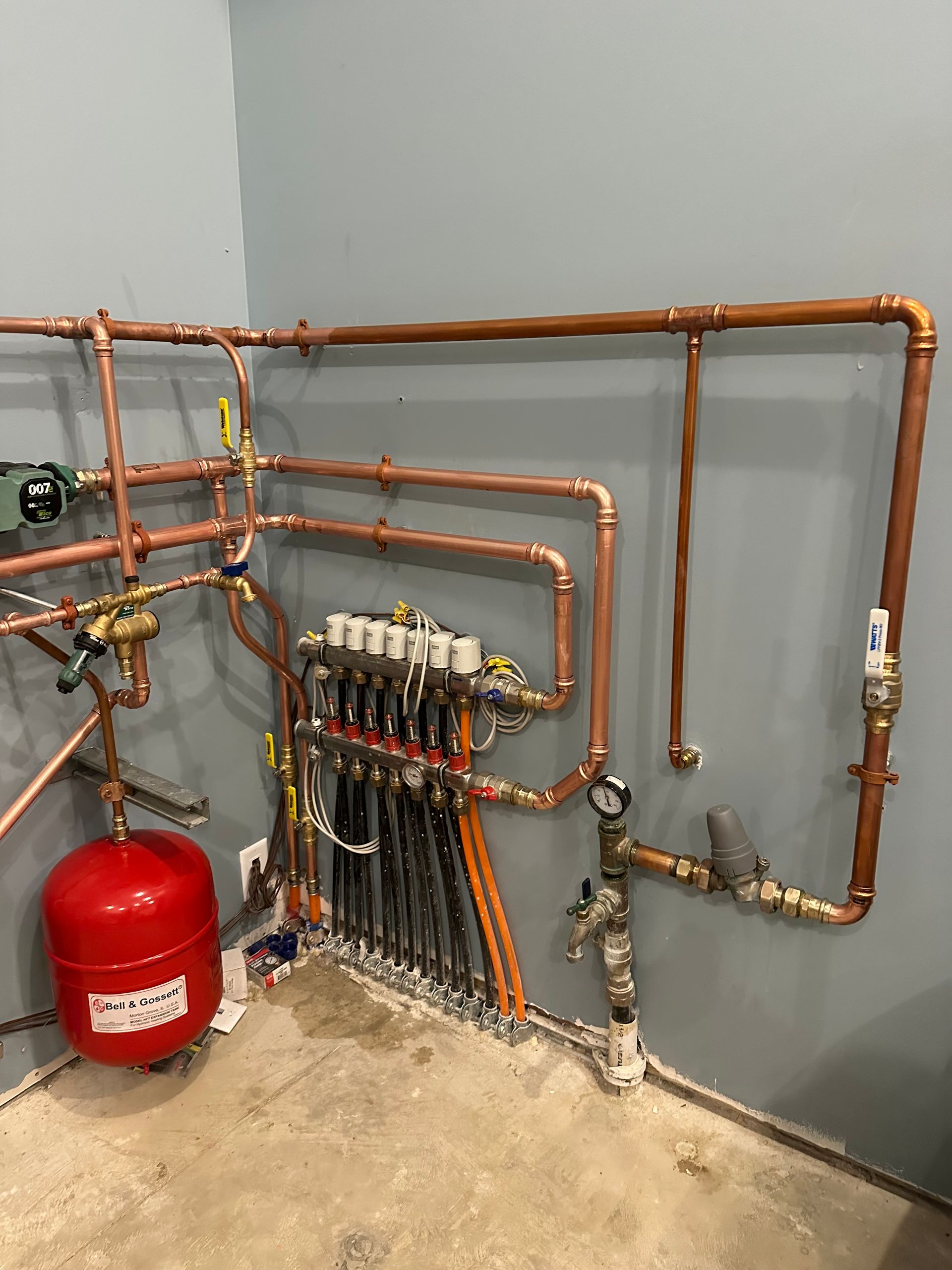 A room filled with copper pipes and a red tank.