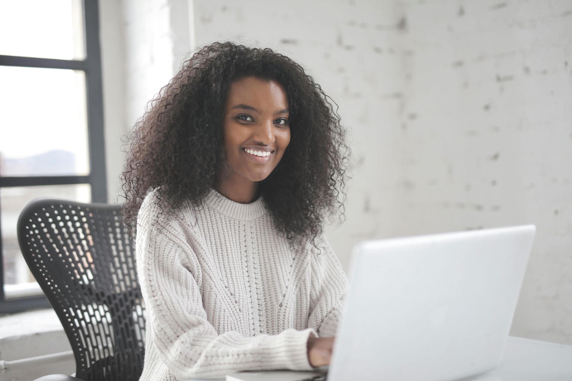 Smiling person working on a computer, looking at the camera, representing affordable SEO services