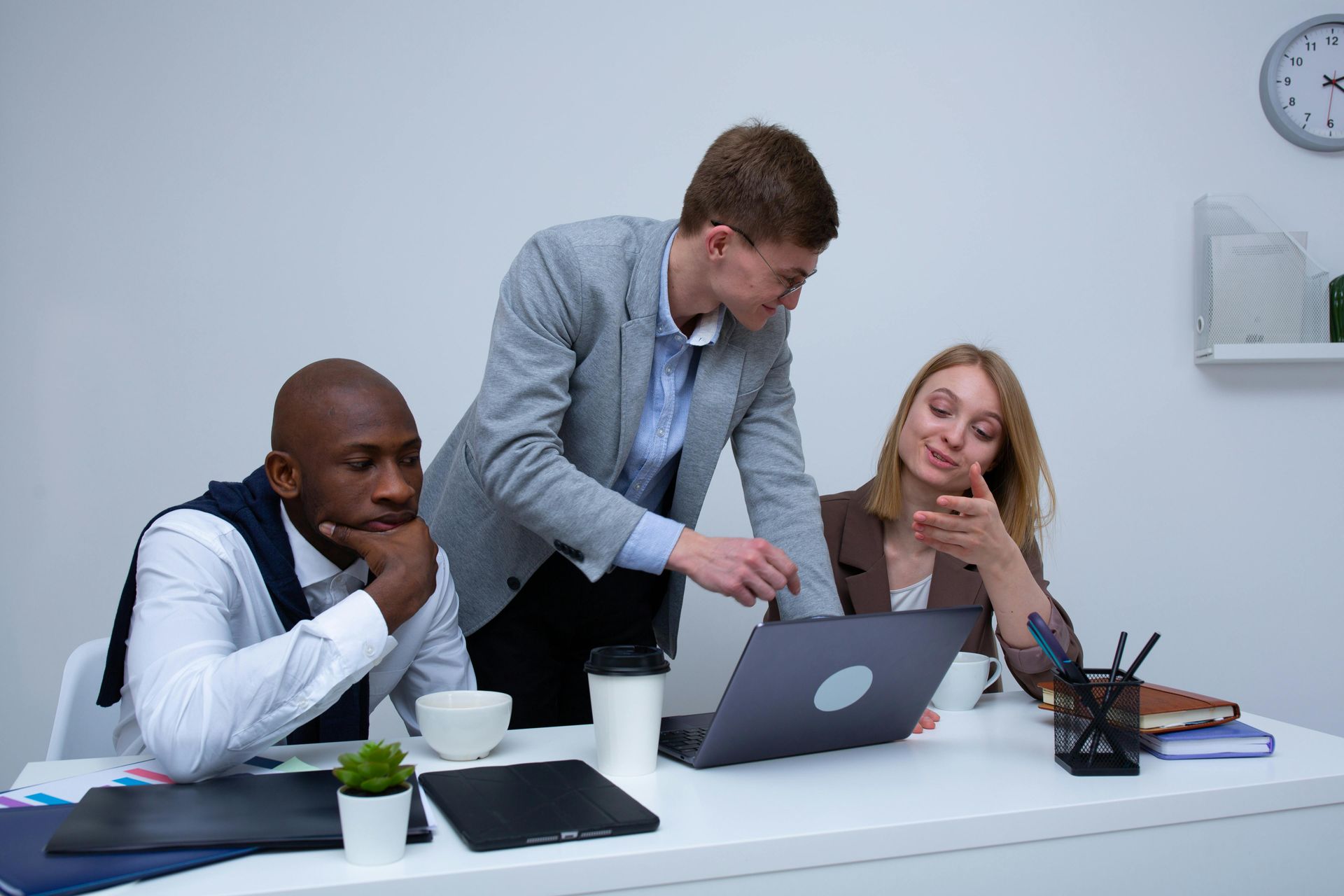 Three professionals sitting together and looking at a laptop, collaborating on local marketing strategies. Three professionals sitting together and looking at a laptop, collaborating on local marketing strategies.