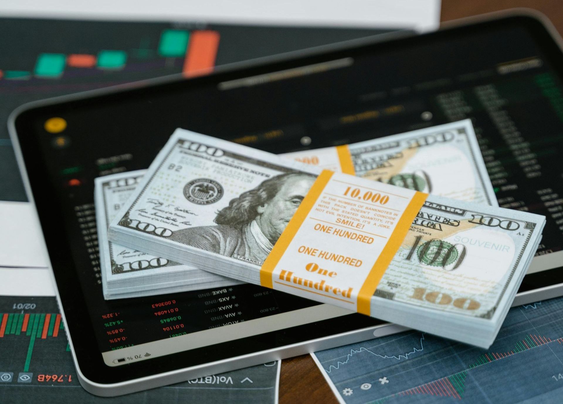 A stack of money placed on top of graphs and charts A stack of money placed on top of graphs and charts