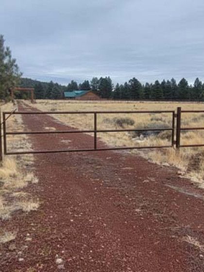 Wooden gate at Lazy B Ranch with a rustic sign and open ranch entrance under a blue sky