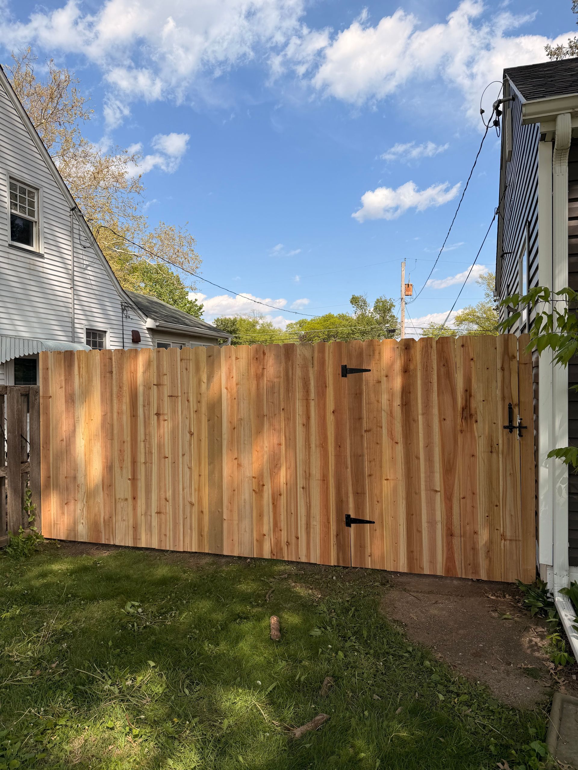 Wooden privacy gate between two houses with grass and a blue sky overhead