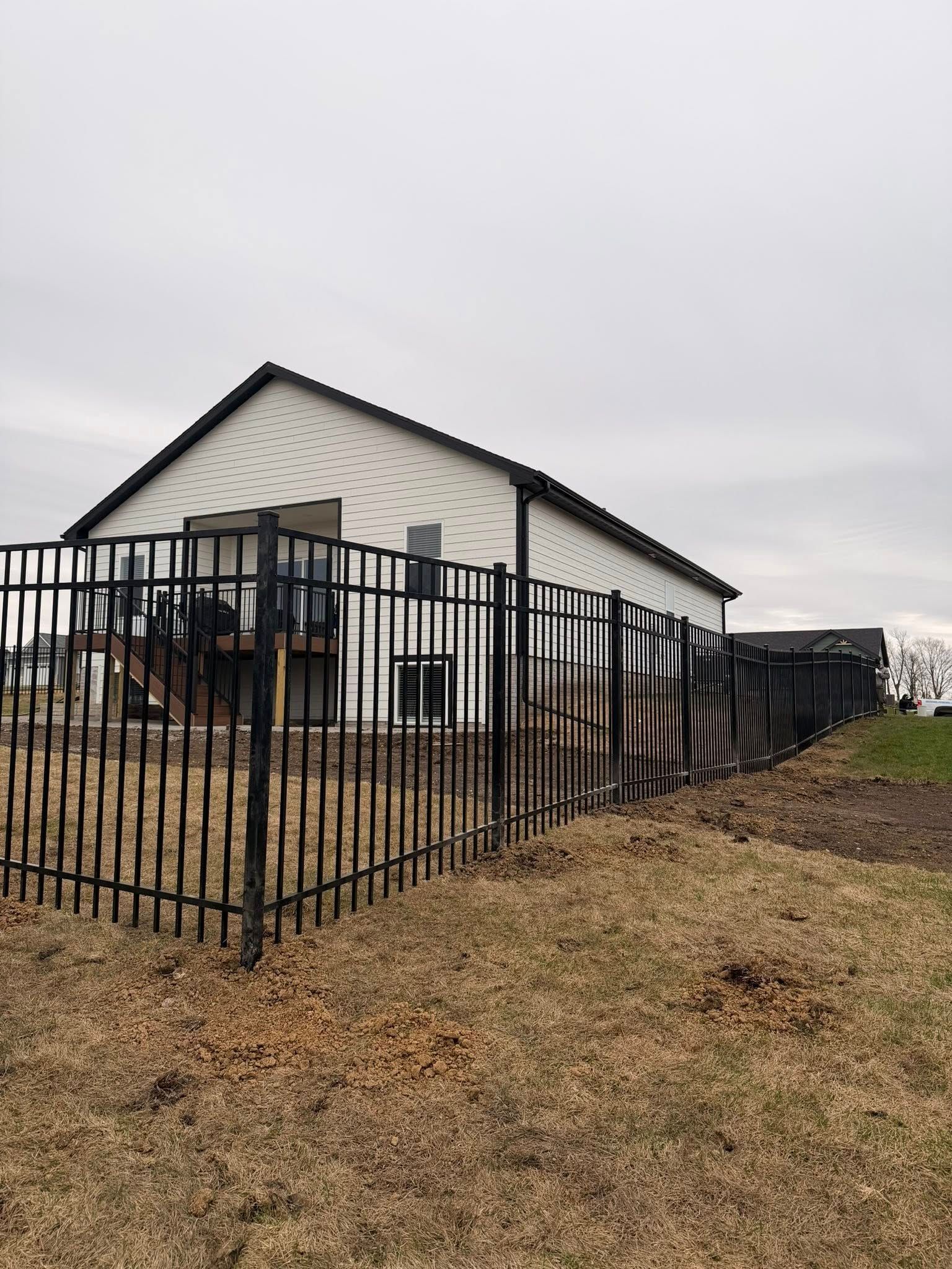 Black metal fence around a white house on a cloudy day