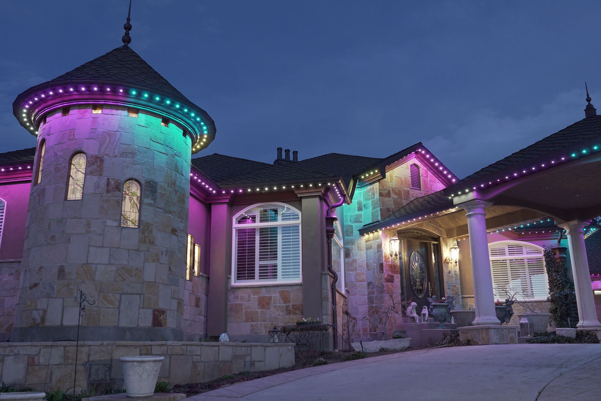 A large house with purple and green lights on it at night.