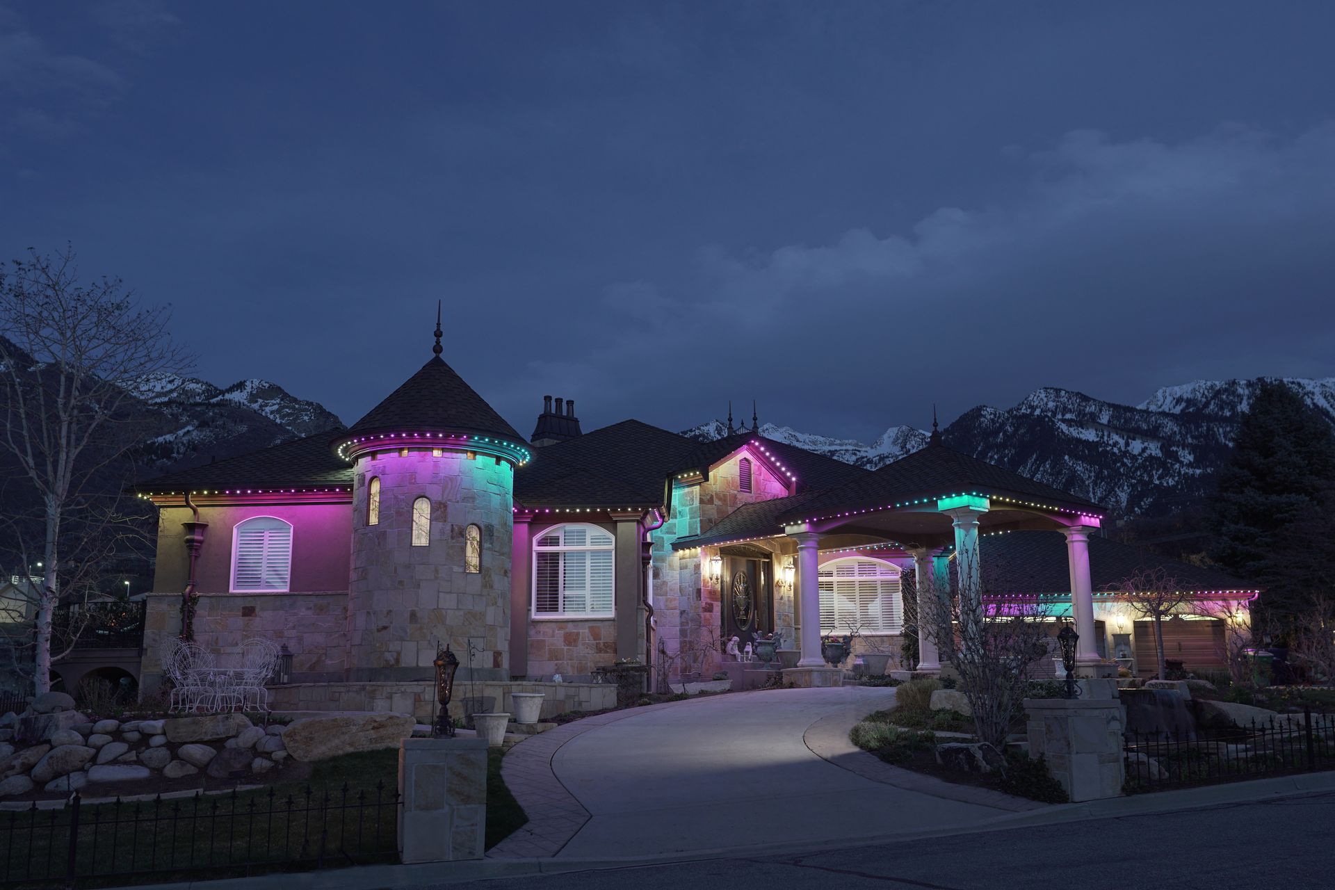 A large house is decorated with christmas lights at night.