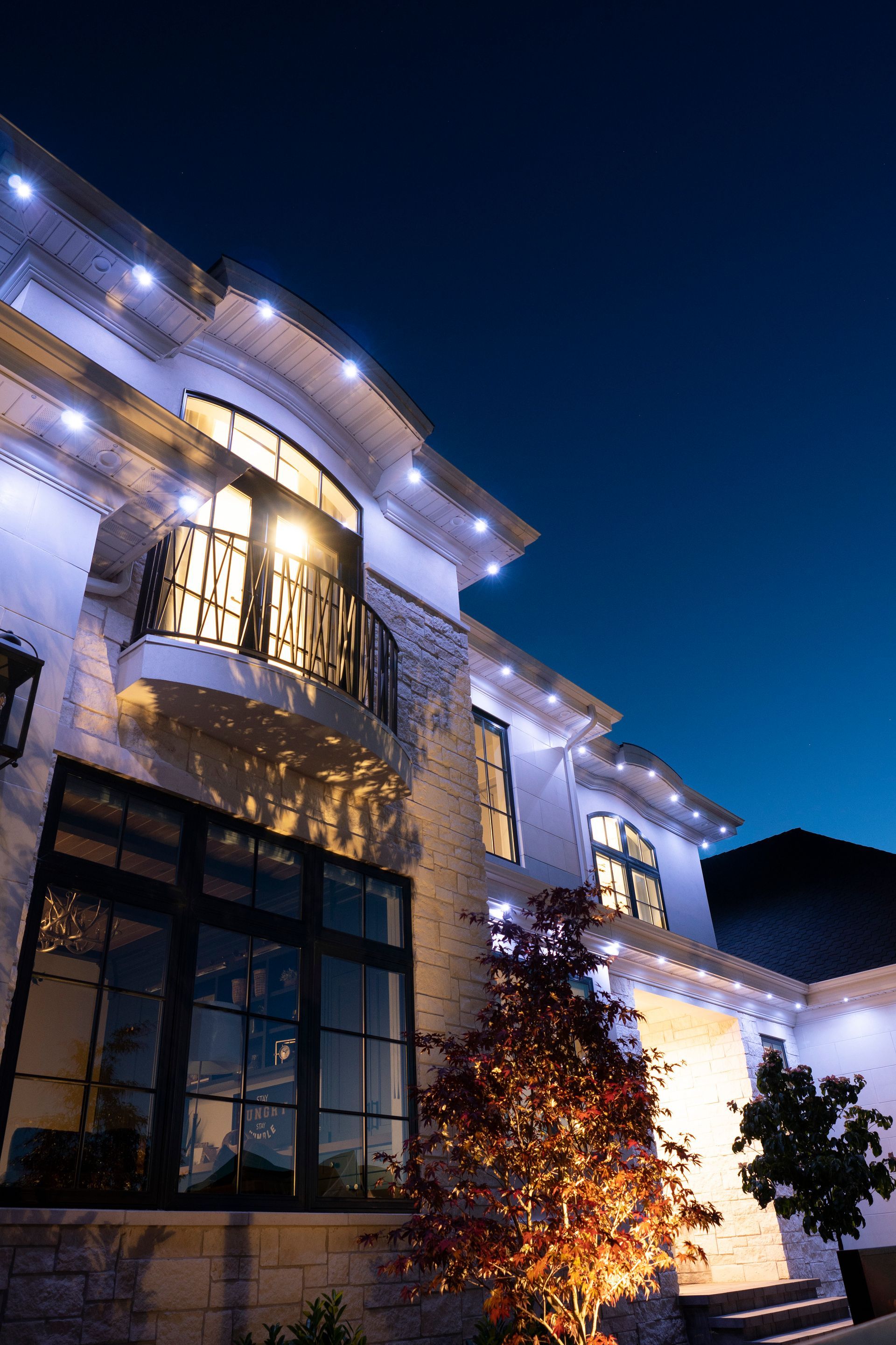 A large white house is lit up at night with christmas lights.