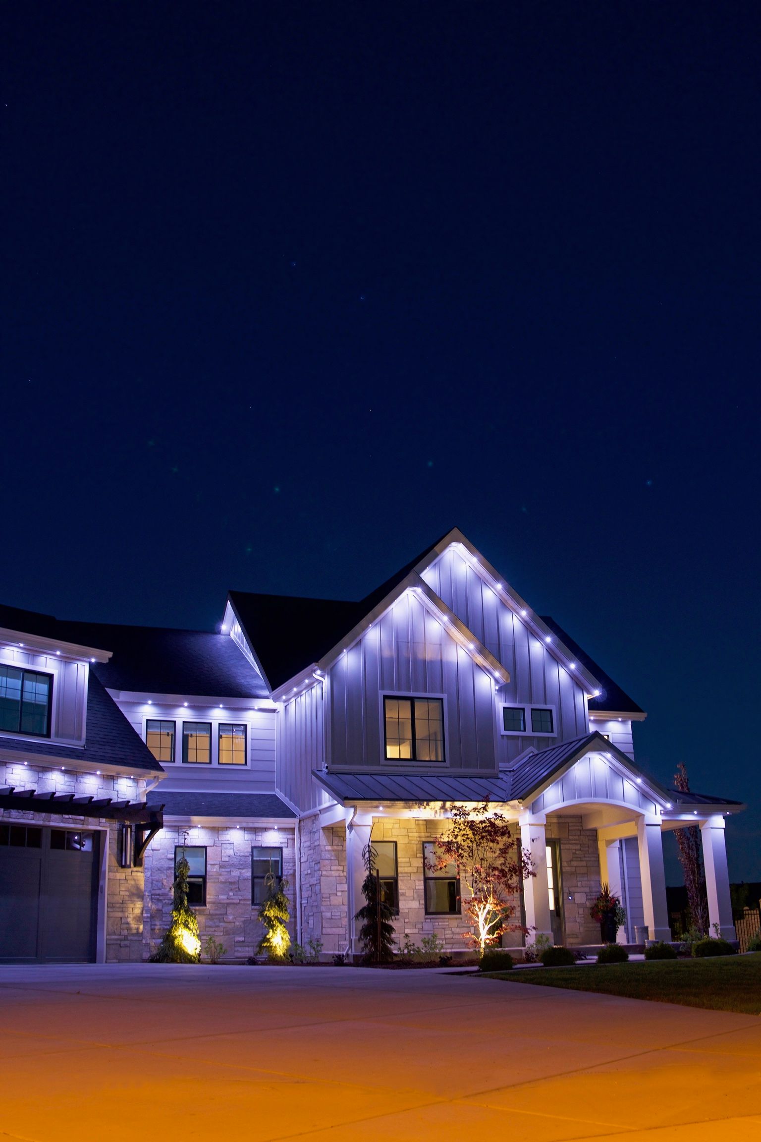 A large white house is lit up at night with christmas lights.