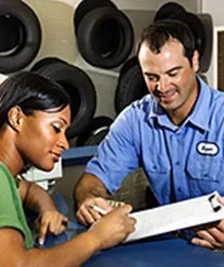 Woman and mechanic reviewing a clipboard in a tire shop.
