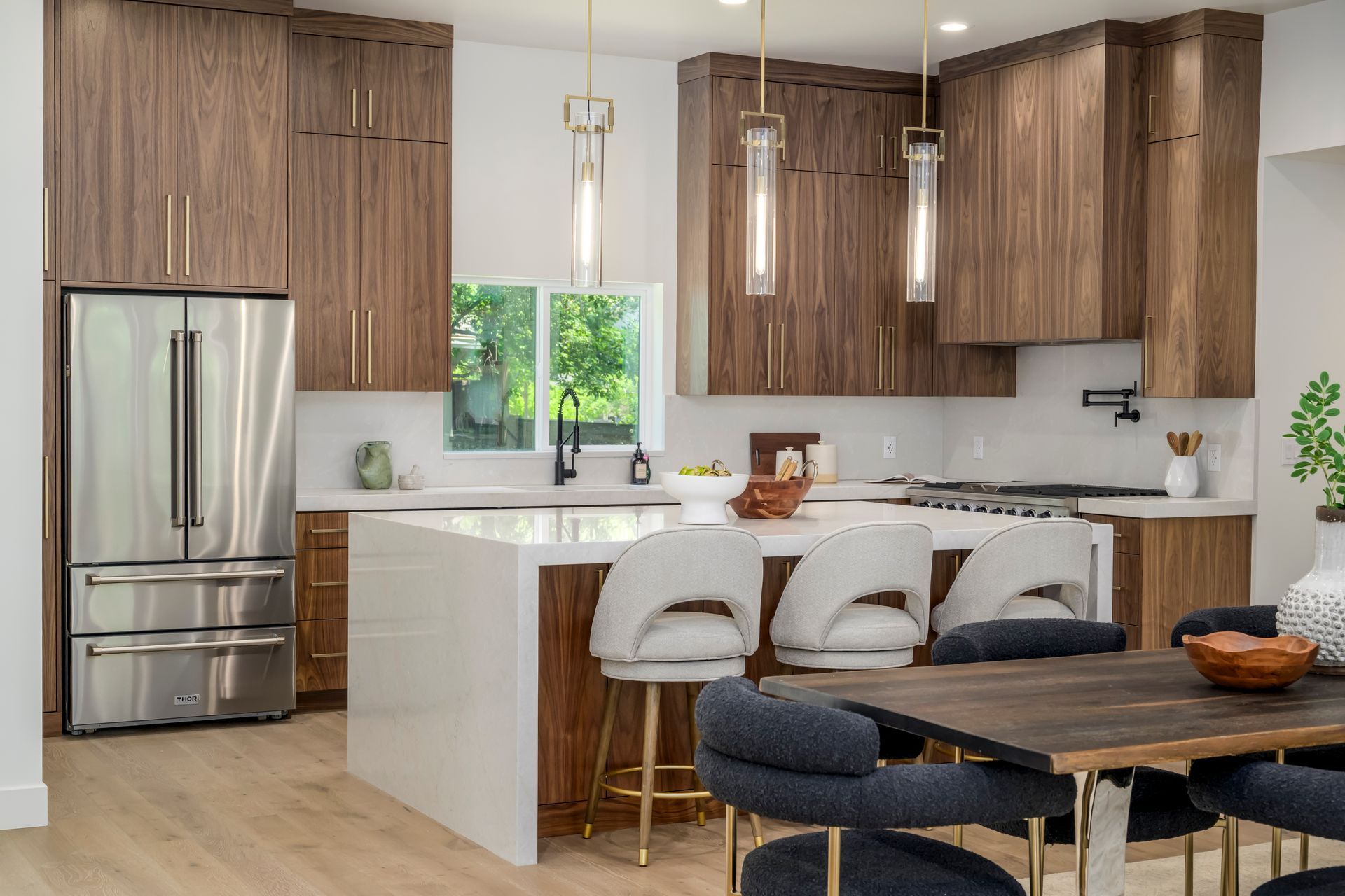 Modern kitchen with walnut cabinets, white countertops, and bar seating.