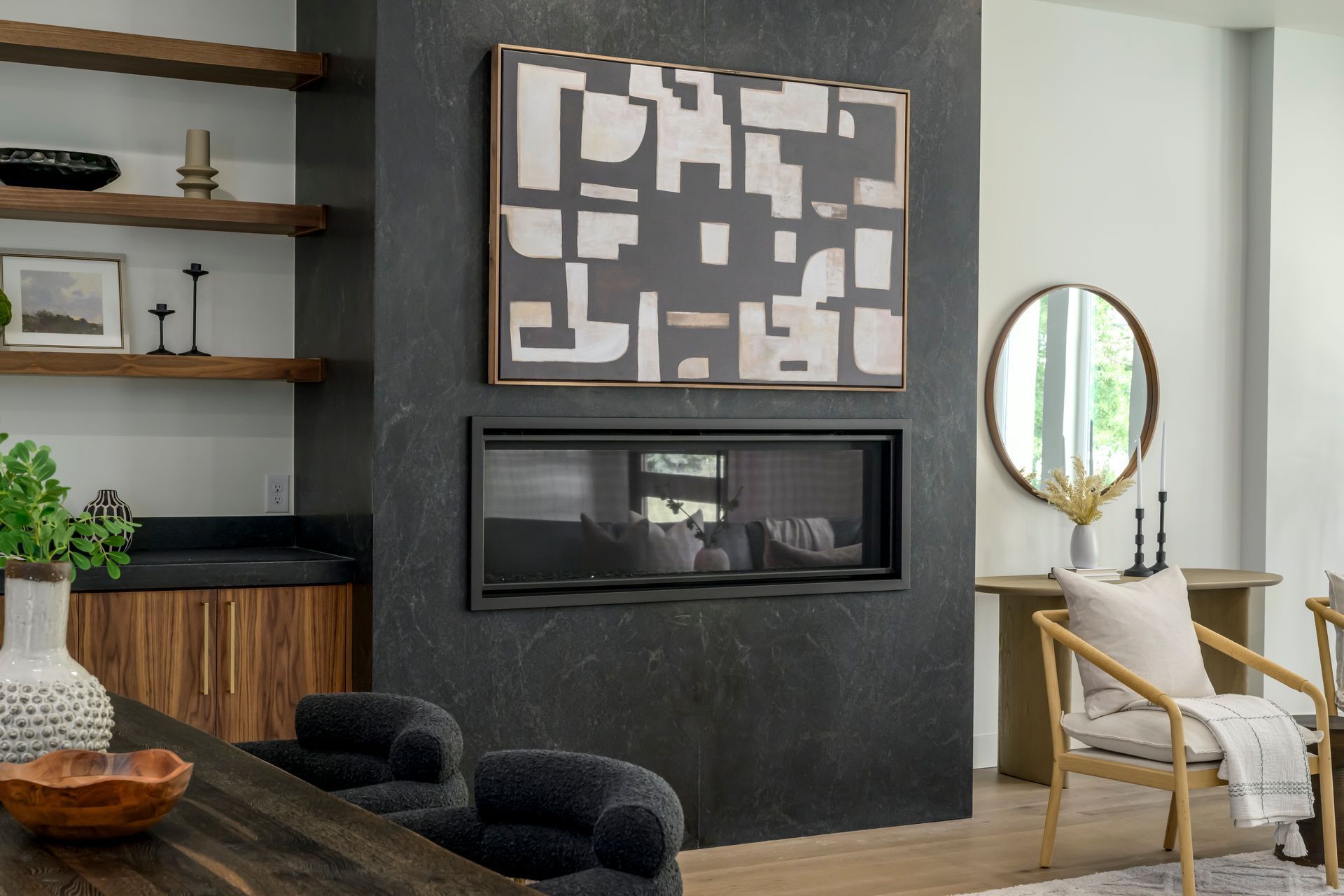 Modern living room with fireplace, art, and built-in shelving, dark gray and wood tones.