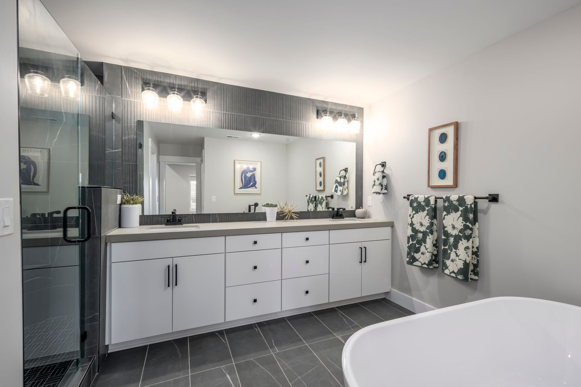 Modern bathroom with white vanity, gray accents, large mirror, and soaking tub.