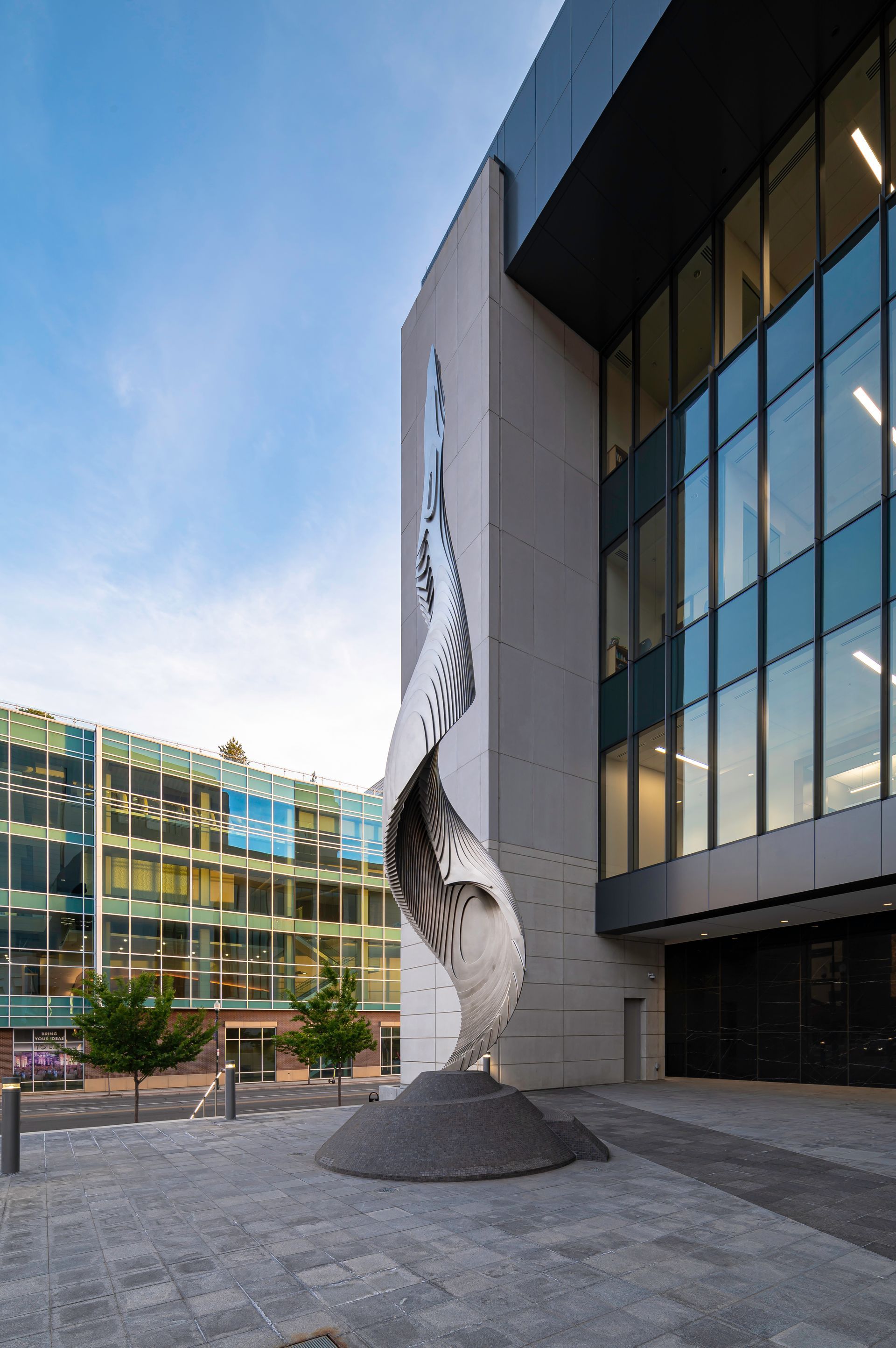 Modern building exterior with a tall abstract sculpture and glass facade
