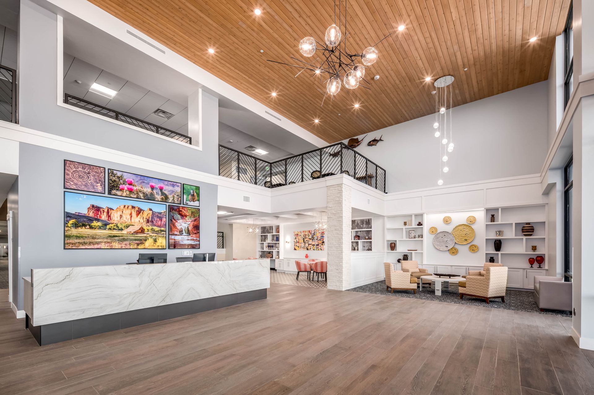 Spacious modern lobby with wood ceiling, white walls, reception desk, seating area, and colorful wall art