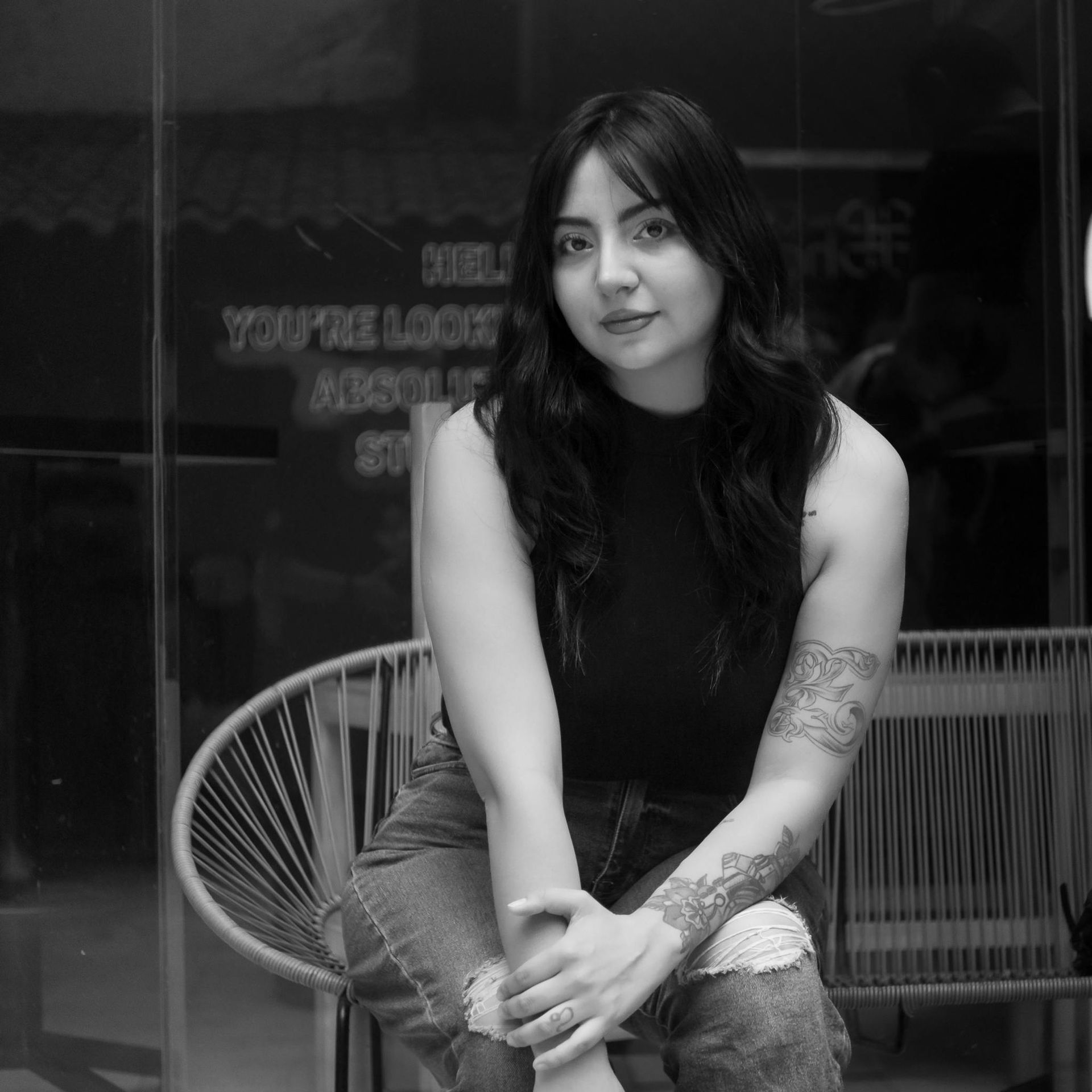 A woman is sitting in a chair in front of a sign that says help you 're lost
