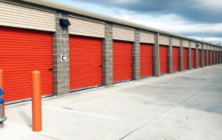 A row of red garage doors are lined up in a parking lot.