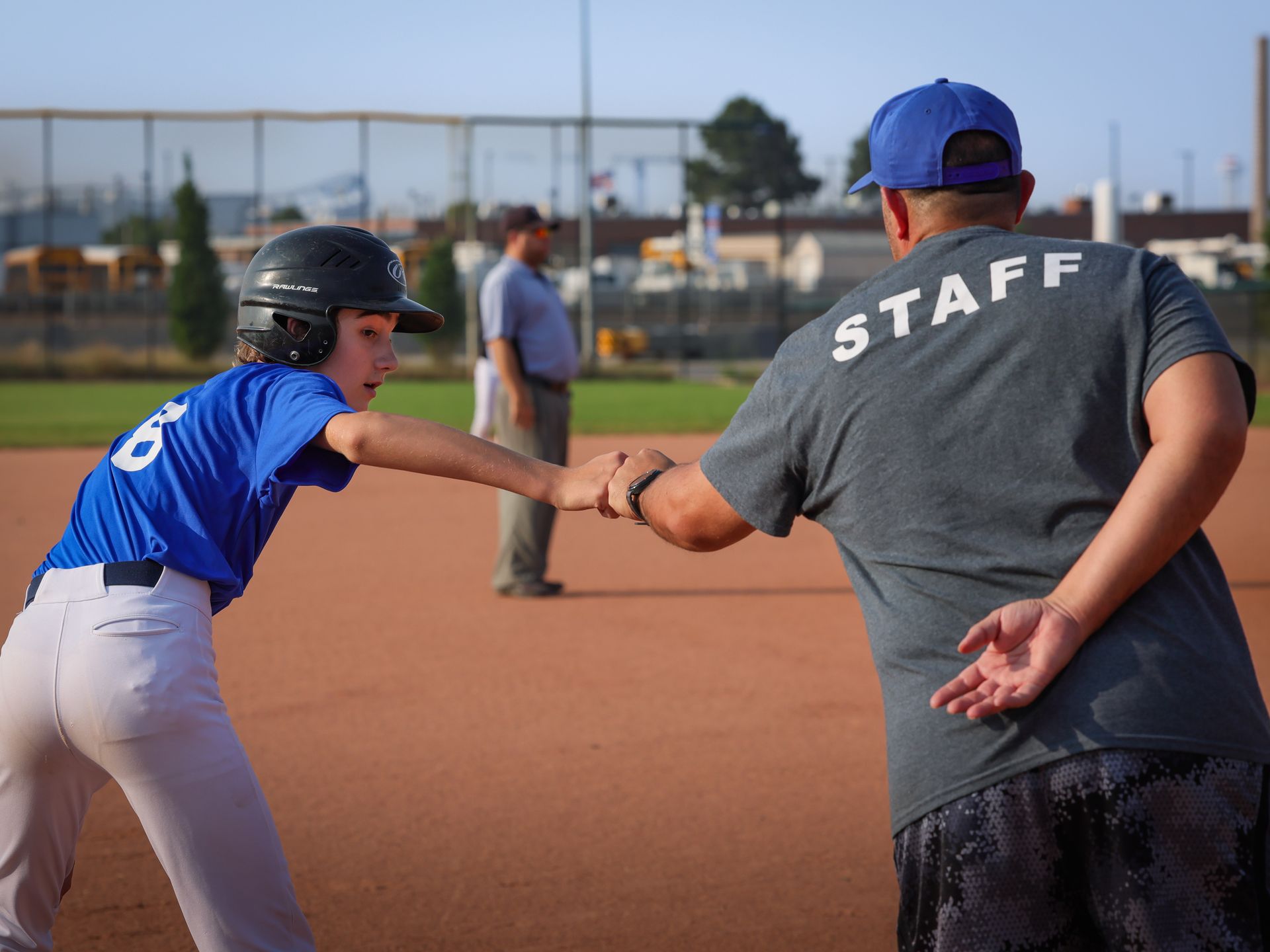 Baseball coach giving his player a high five from thrid base