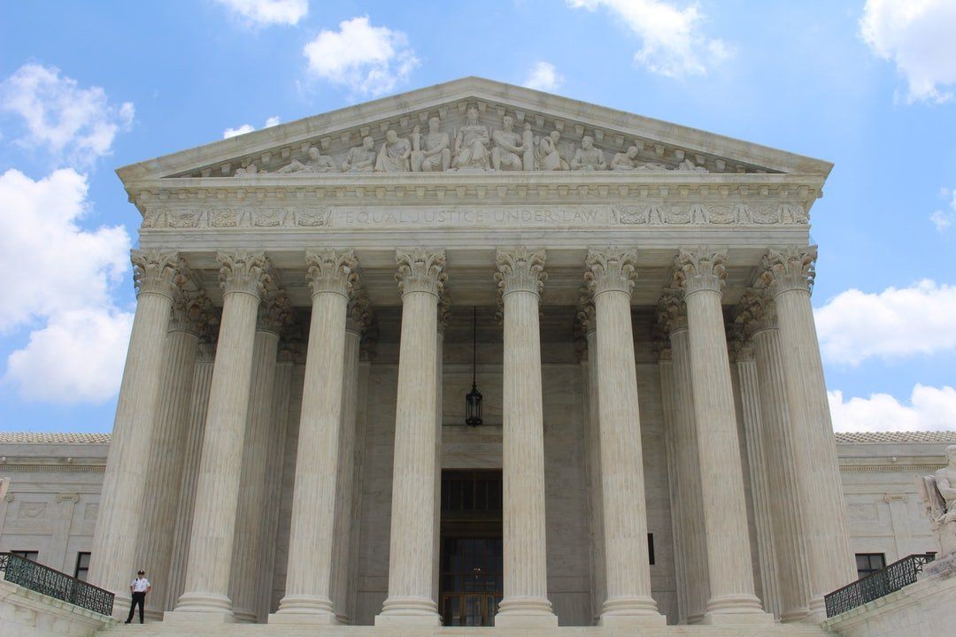 United States Supreme Court building with tall white columns and classical pediment against a blue sky