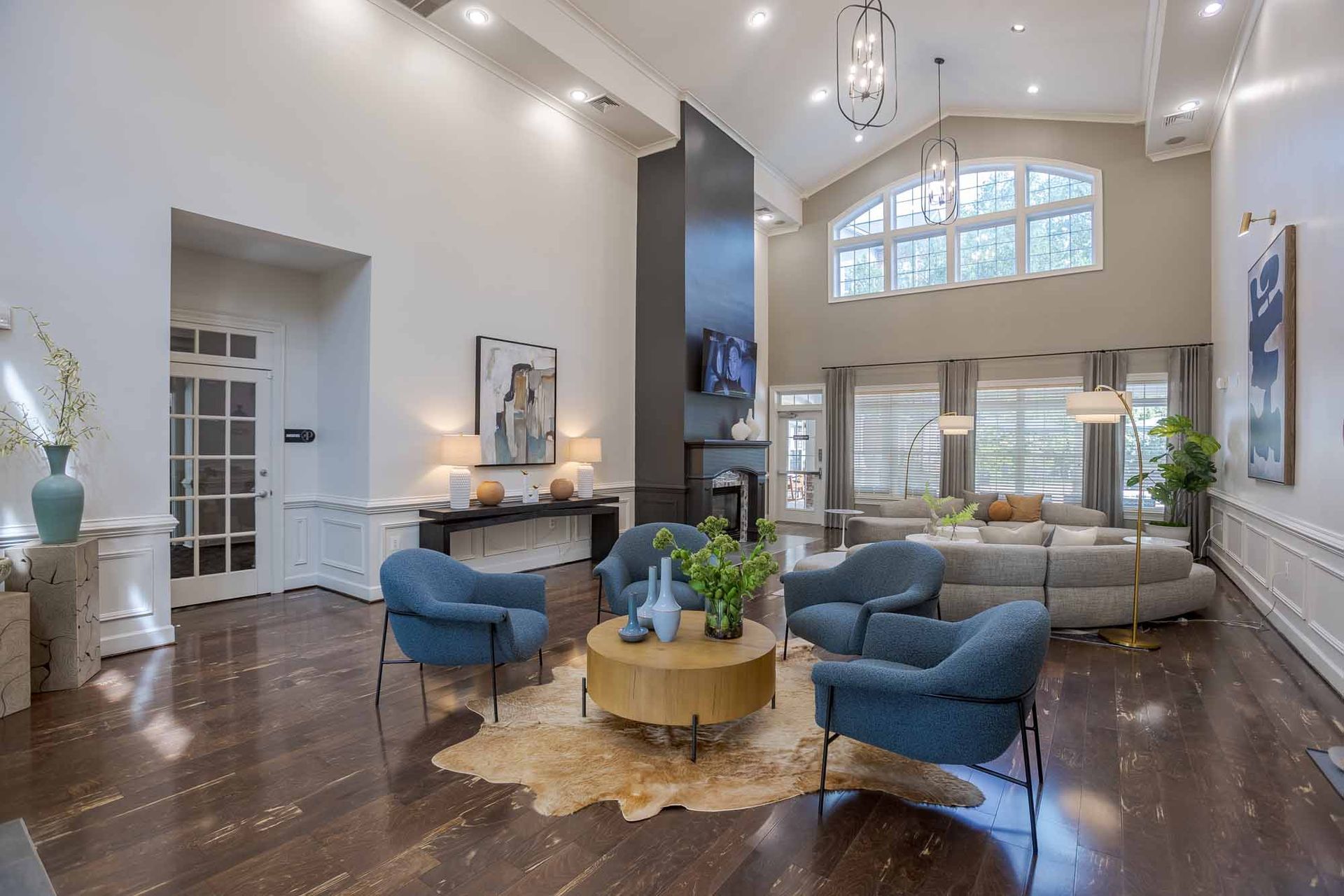 Spacious gray-walled lobby with red chairs, a coffee table, and decorative cabinets. A large window at the far end.