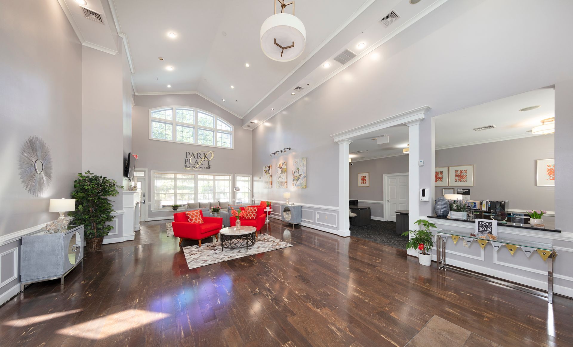 Spacious, bright lobby with red seating, dark wood floor, and large windows.