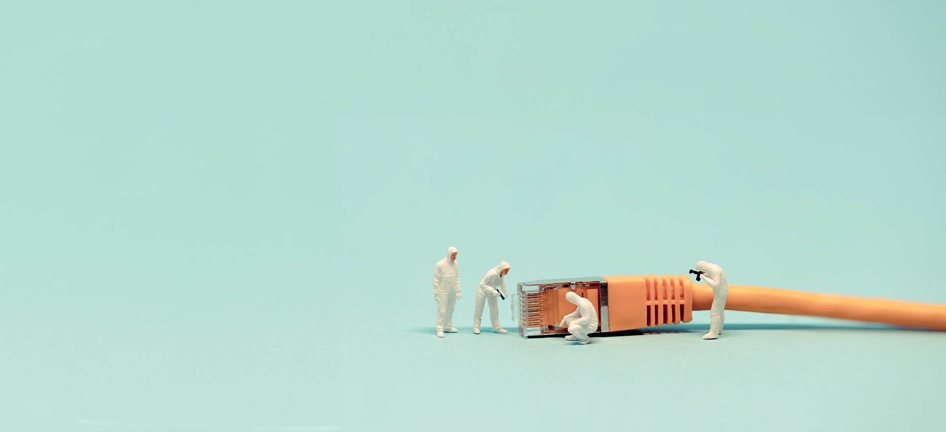 Miniature figures examining a network cable connector against a light blue background.