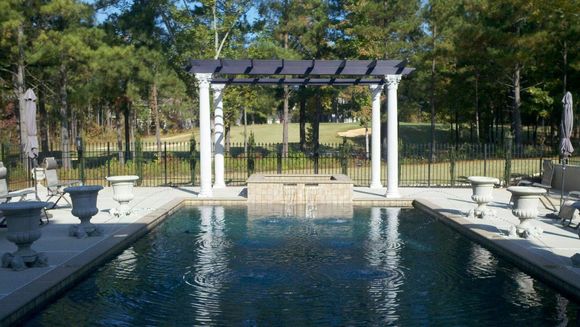 A large swimming pool with a pergola over it