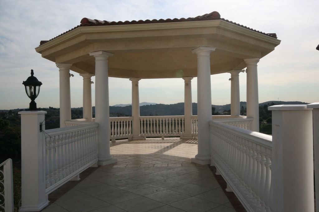 A gazebo with columns and a fence surrounding it