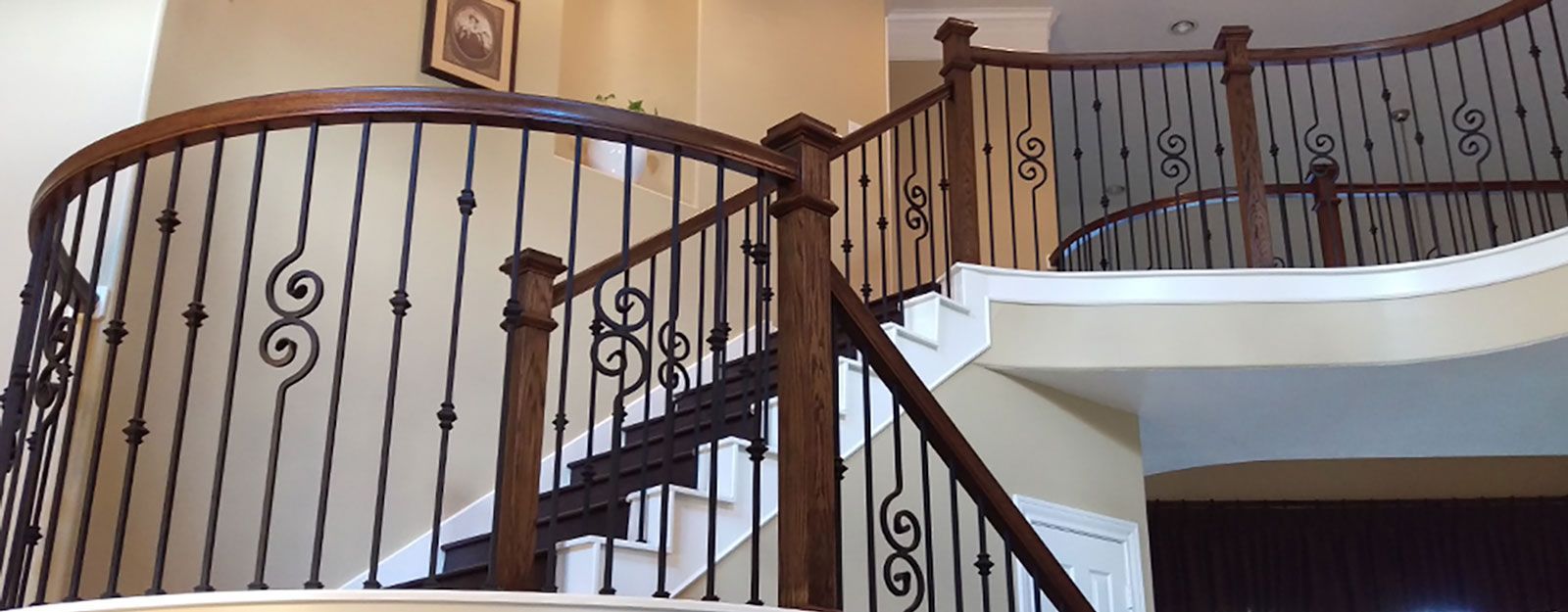 A wooden staircase with a wrought iron railing in a house.