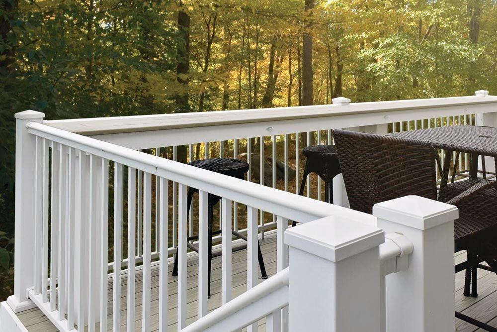 A white railing on a deck with a table and chairs
