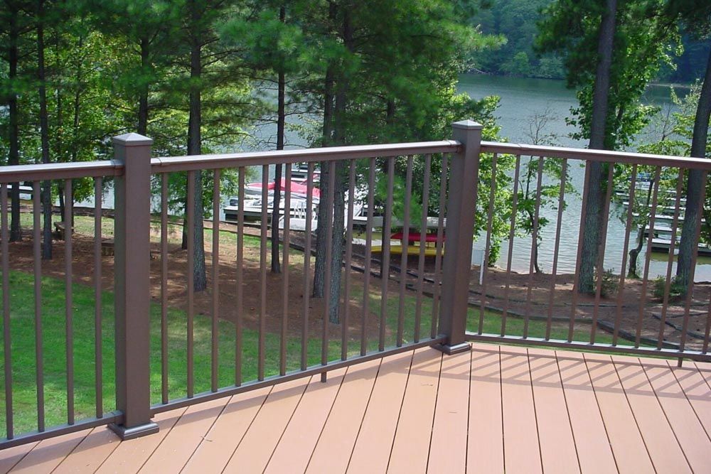 A wooden deck with a metal railing overlooking a lake