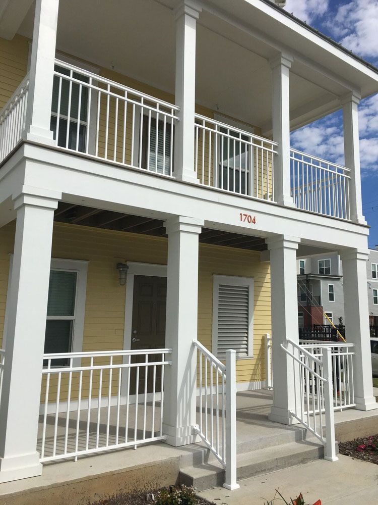 A yellow house with white columns and a balcony