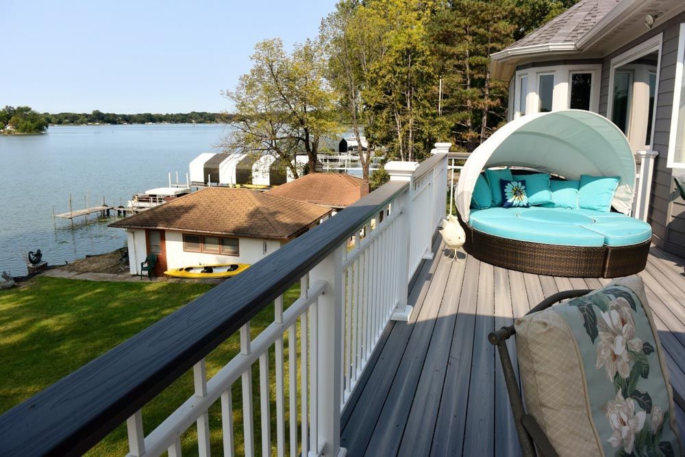 A balcony overlooking a lake with a day bed on it
