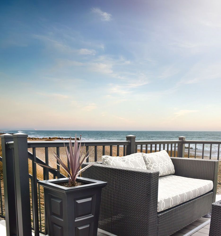 A balcony with a couch and planters overlooking the ocean