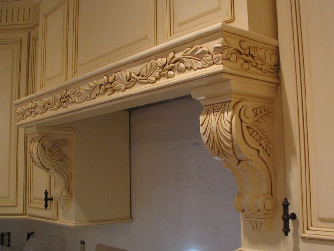 A kitchen with white cabinets and a wooden hood