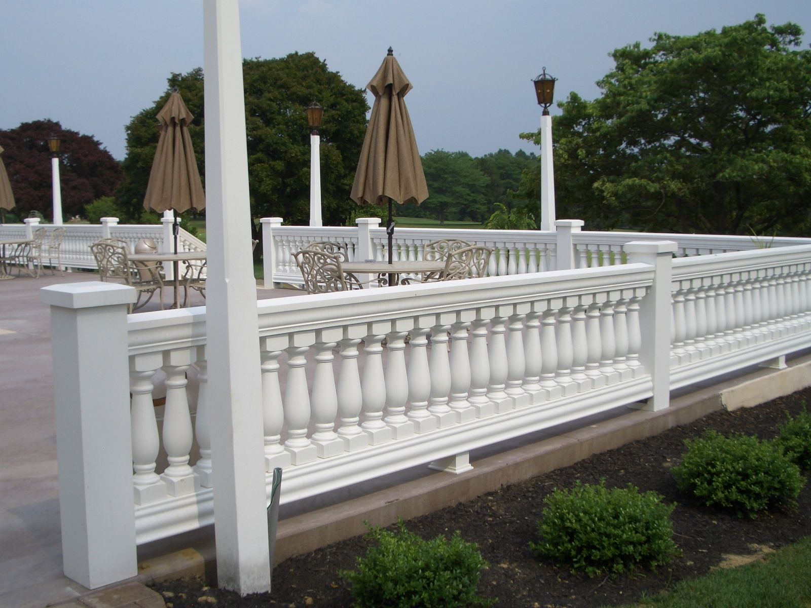 A white railing with tables and chairs behind it