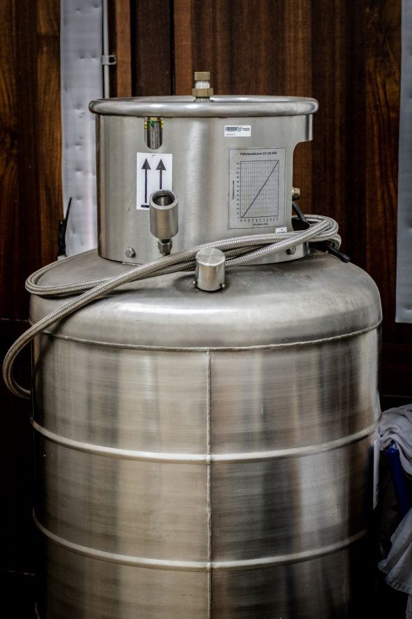 Un grand réservoir en acier inoxydable avec un tuyau attaché.