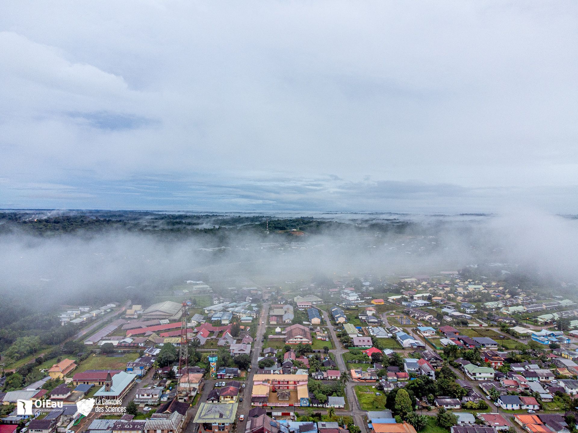 Une vue aérienne d'une ville couverte de brouillard par temps nuageux.