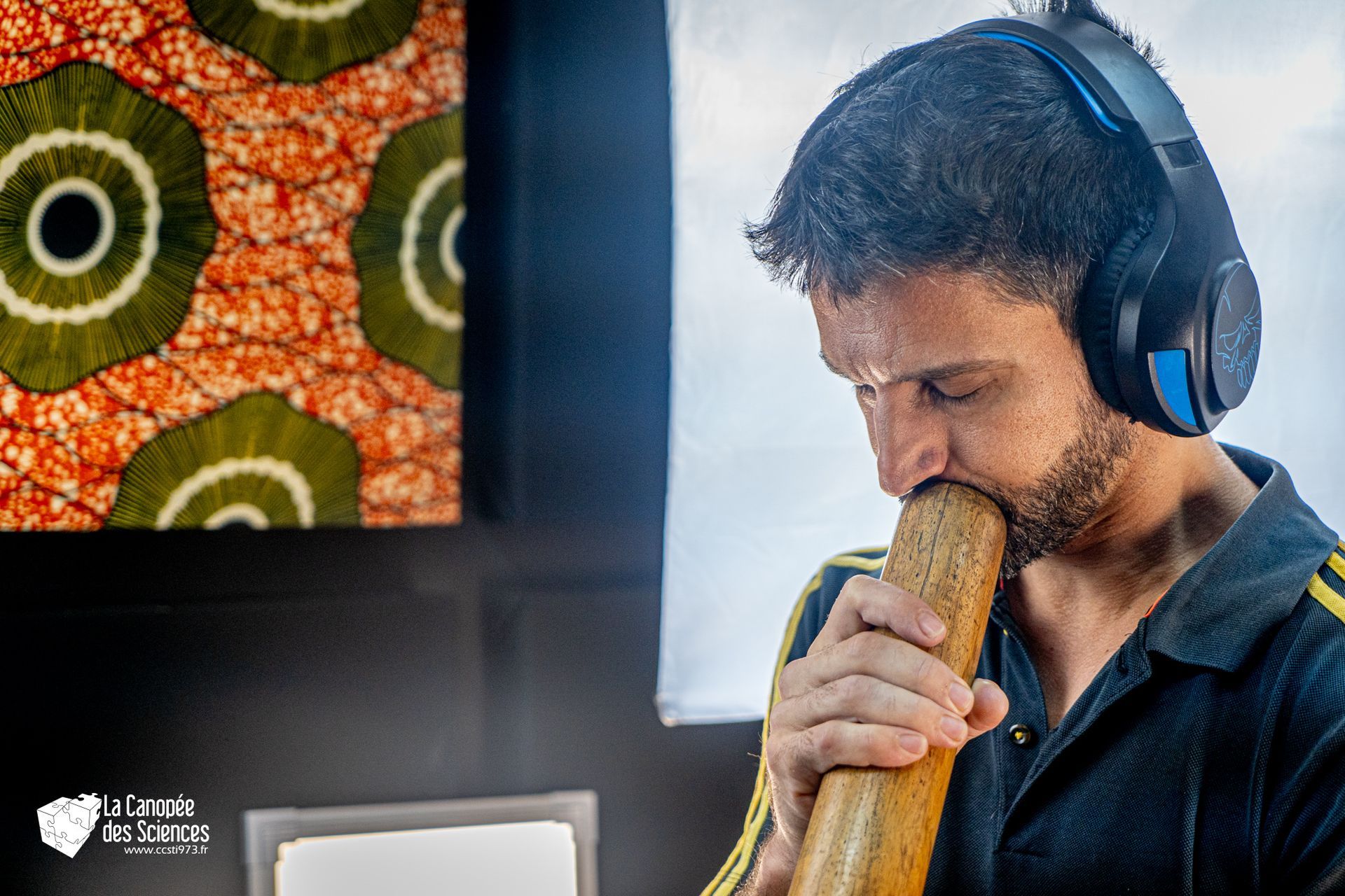 Un homme portant des écouteurs joue du didgeridoo.