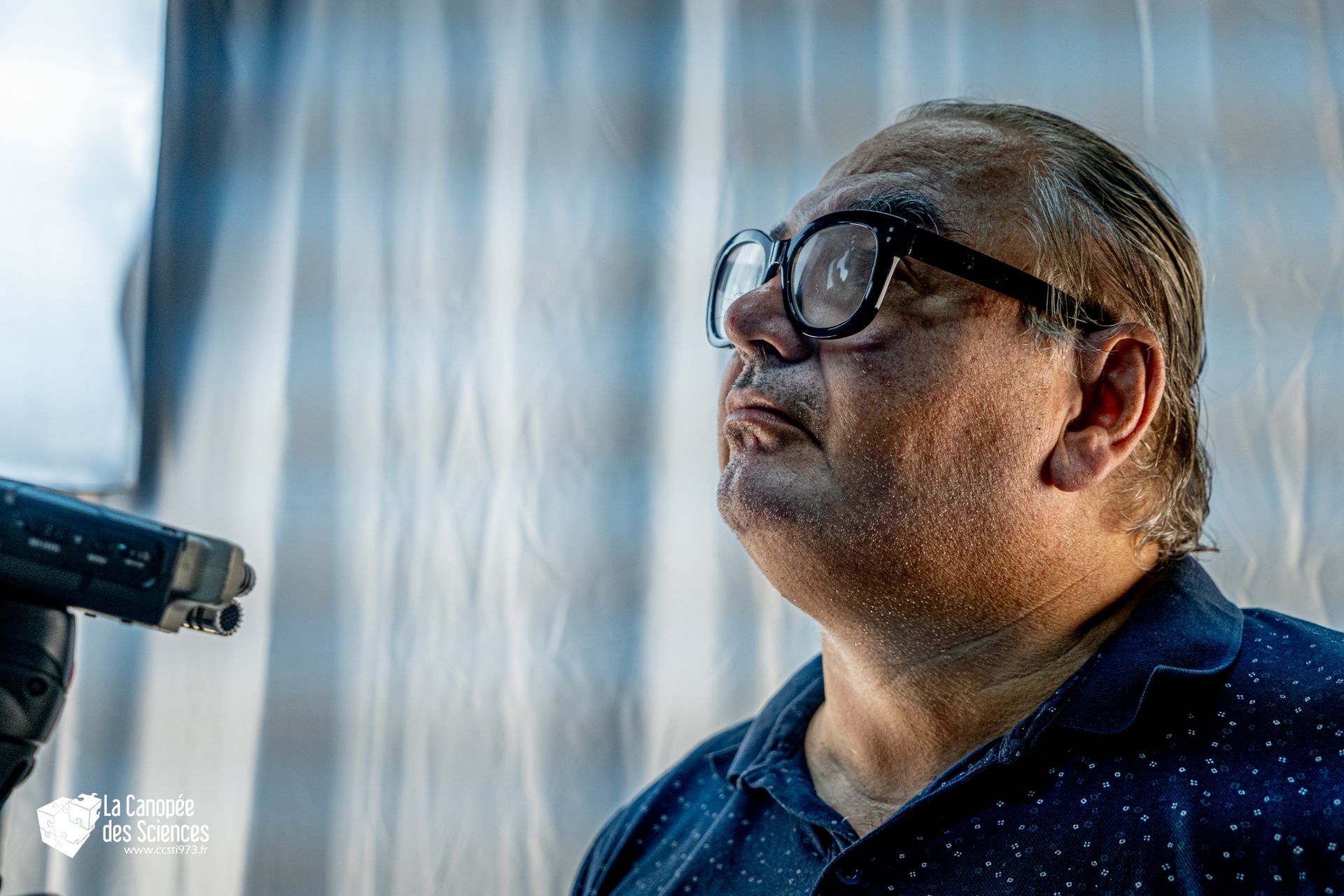 Un homme portant des lunettes regarde le ciel.