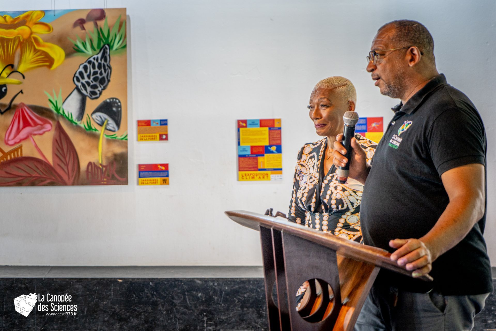 Un homme et une femme se tiennent sur un podium devant un tableau.