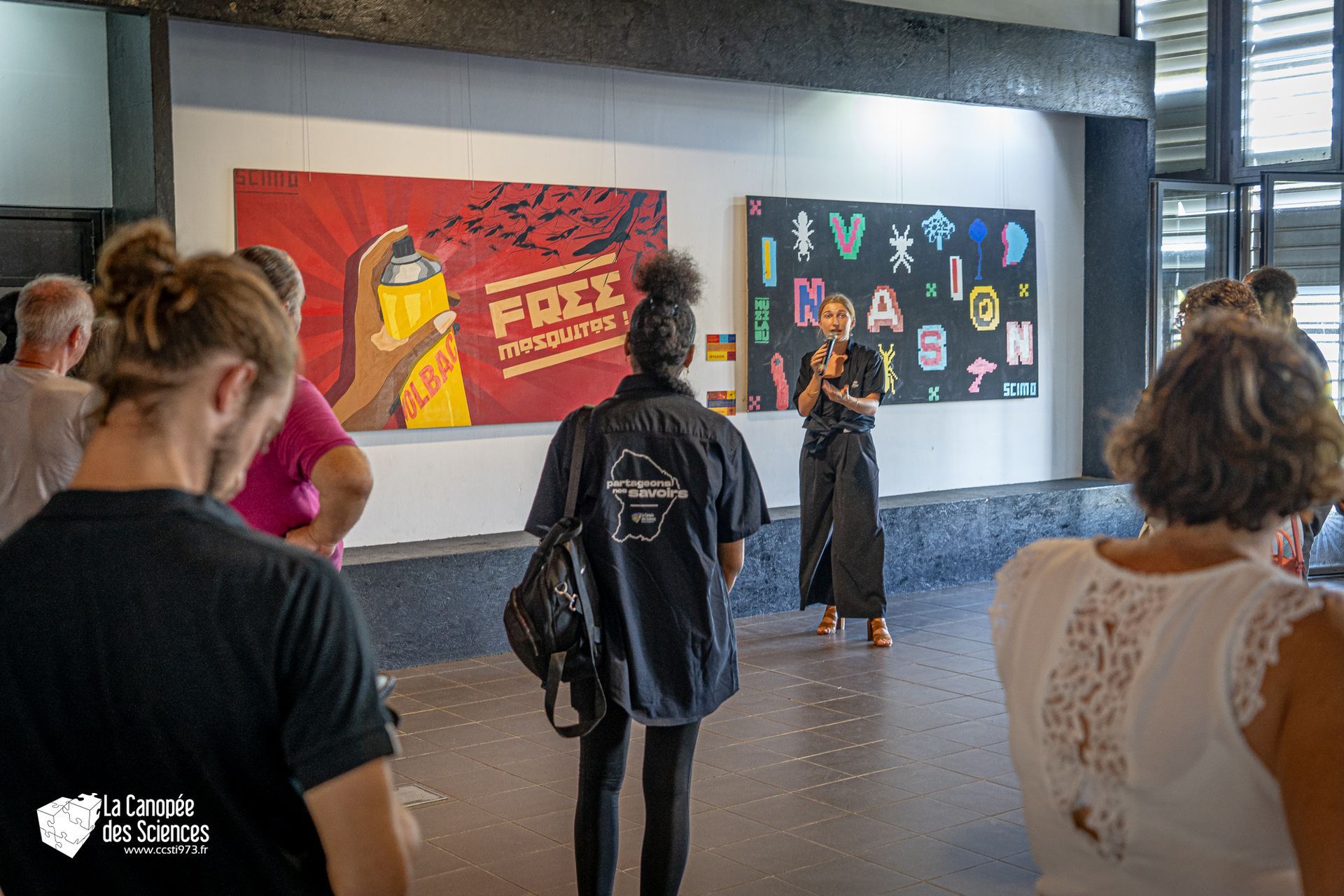 Un groupe de personnes se tient devant un mur avec un tableau dessus.