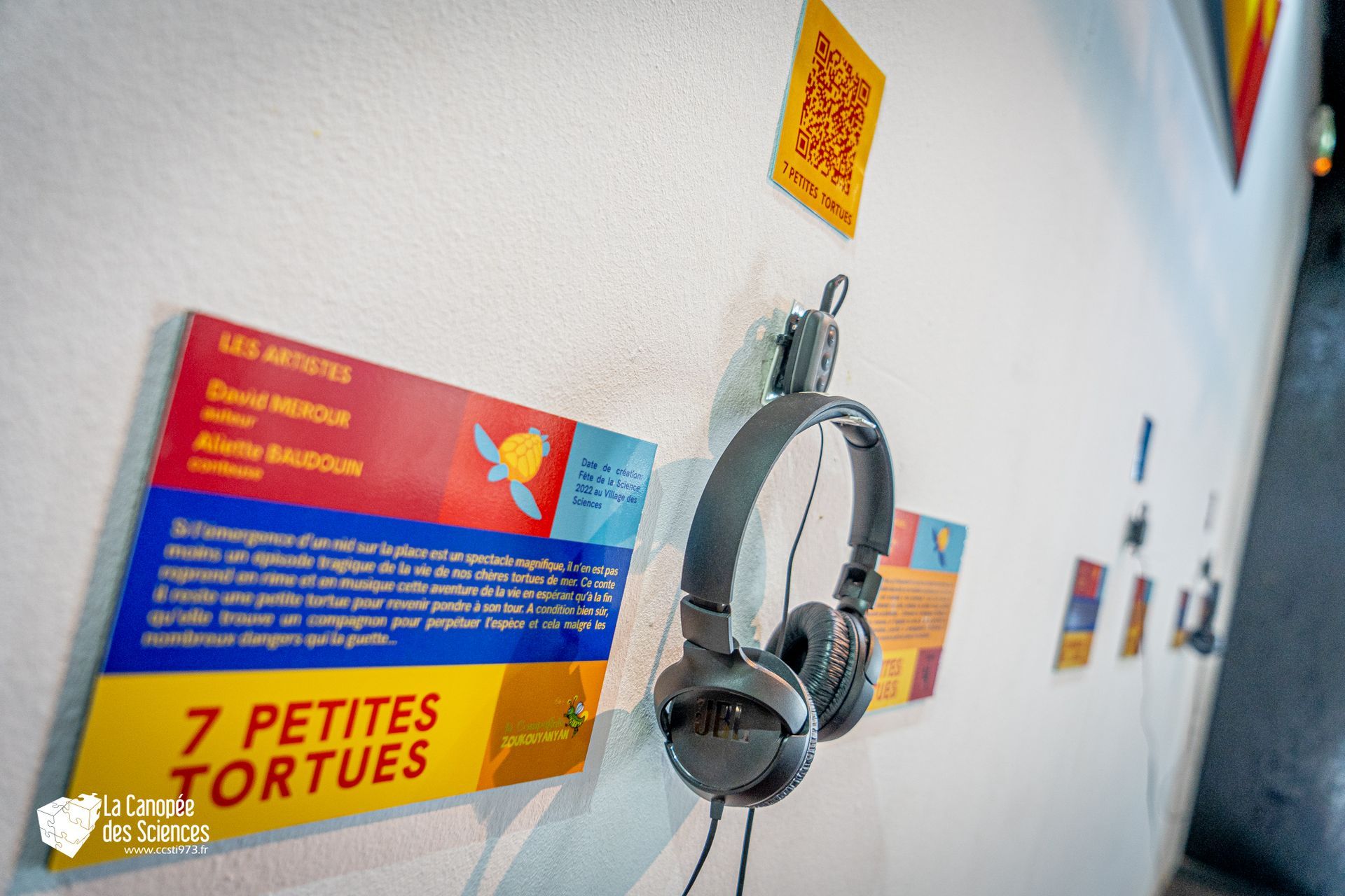 Une paire d'écouteurs accrochée au mur à côté d'un panneau indiquant 7 petites tortues