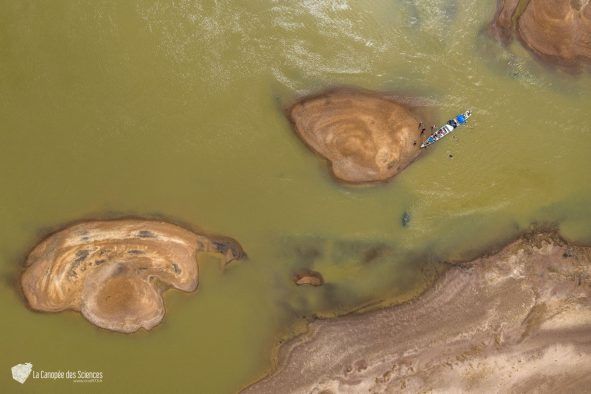 Une vue aérienne d'une rivière avec des rochers et un bateau dans l'eau.